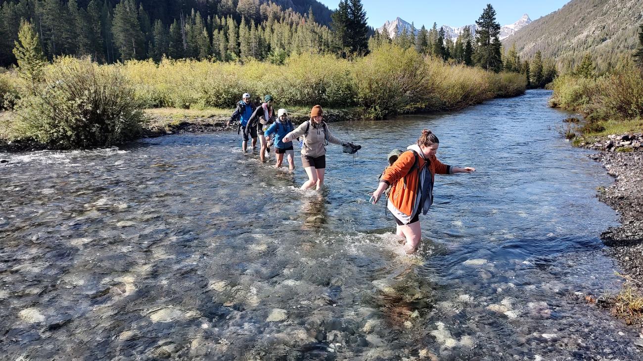 Students walk across a river during Field Camp.